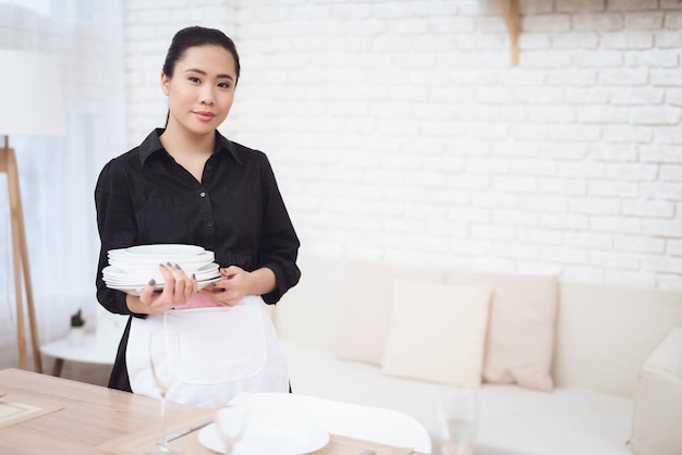 Hübsches Mädchen-thailändisches Hausmädchen mit weißen neuen Platten.