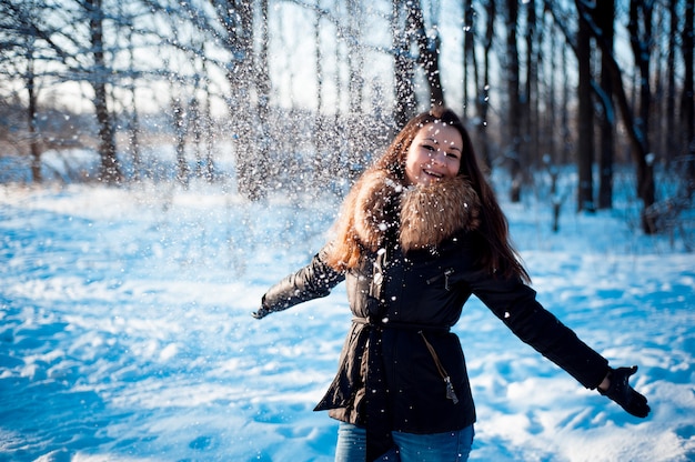 Hübsches Mädchen wirft Schnee in einem Winterpark