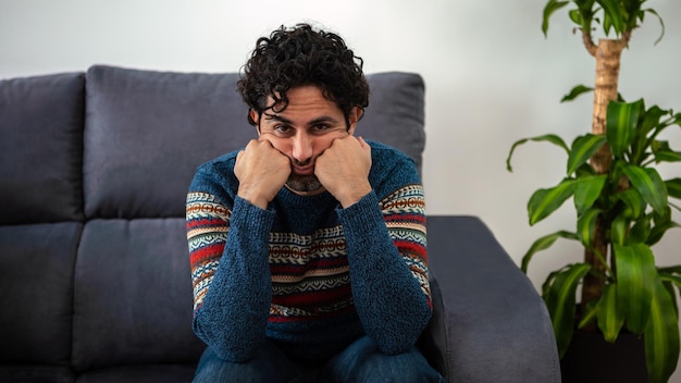 Hübsches männliches Model fühlt sich nach der Arbeit müde. Reifer Mann, der seine Stirn hält, während er Kopfschmerzen hat, während er auf der Couch zu Hause sitzt. Unangenehme Schmerzen.