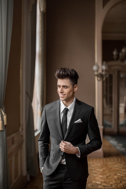Hübsches männliches Modell in einem neuen Anzug in einem schönen Raum