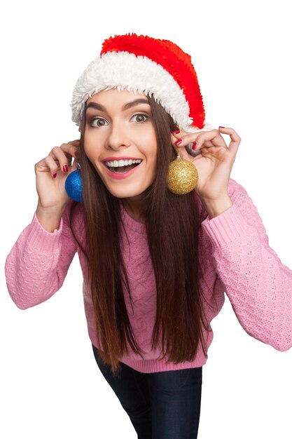 Hübsches Modell im Weihnachtsmann-Hut, der dekorative Weihnachtskugeln hält