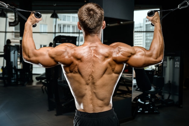 Hübsches Modell junger Mann, der zurück im Fitnessstudio trainiert