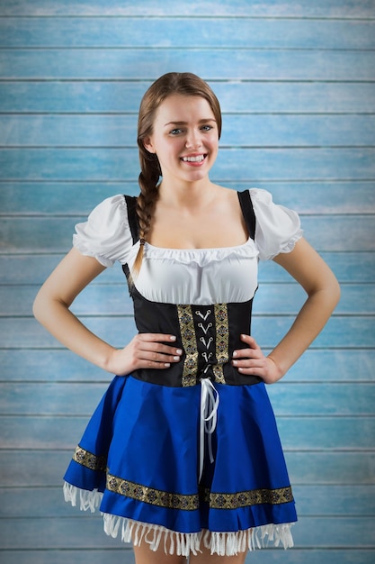 Hübsches oktoberfest-mädchen, das in die kamera gegen holzbohlen lächelt