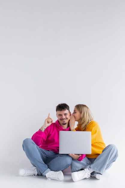 Hübsches Porträt eines Paares mit Laptop auf grauem Hintergrund