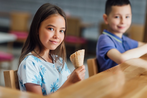 Hübsches, süßes Mädchen mit Eis, das sich mit ihrem Bruder im Café ausruht und sehr schöne Zeit verbringt.