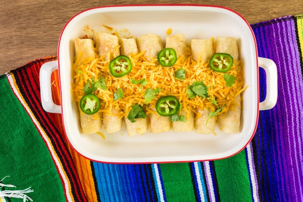 Foto hühnchen-enchiladas mit cheddar-käse und sauce.