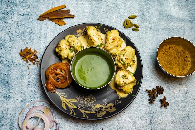 Hühnchen Reshmi Tikka Boti Kabab mit geschmolzener Butter und Chilisauce serviert in einem Gericht isoliert auf grauem Hintergrund Draufsicht auf bangladeschisches Essen