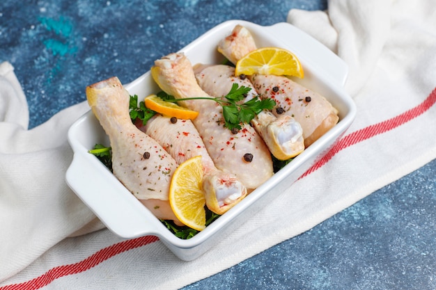 Hühnerbeine mit Gewürzen und Salz bereit zum Kochen auf Schneidebrett.