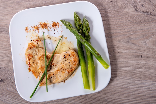 Hühnerbrust mit frischem Spargel auf weißem Teller