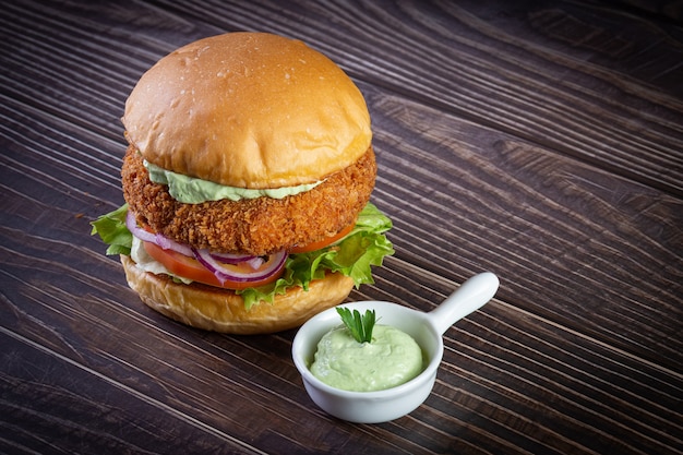 Hühnerburger mit Salat, Tomate, Purpurzwiebel und handgemachtem Mayo auf dem Holztisch. Lecker.