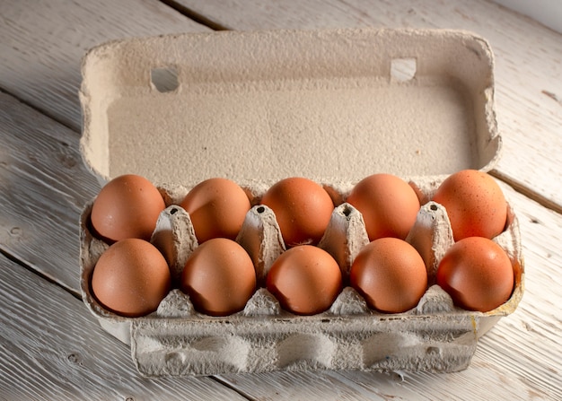 Hühnereier im Kartonständer oder im Eierkarton auf weißem Tisch