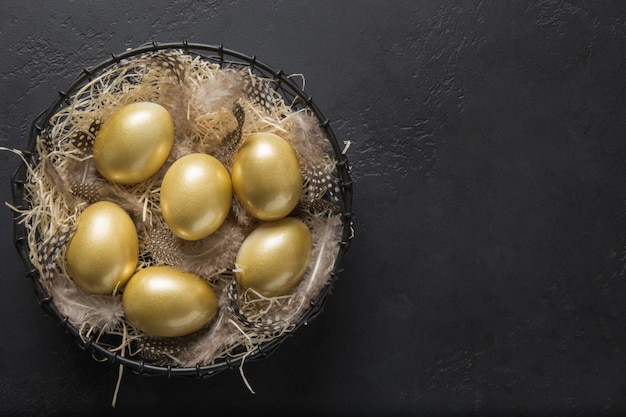 Foto hühnerfarbene goldene eier in dekorativer vase auf schwarz. osterdunkelkonzept. draufsicht und kopierraum.