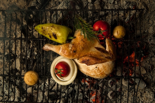 Hühnerfleisch mit Gemüse auf einem Metallgrill auf Holzkohle legen Das Gericht wird auf Holzkohle gekocht und geräuchert