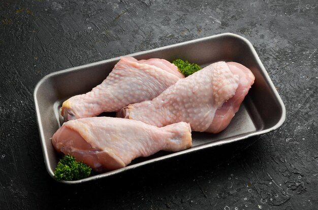 Hühnerfleisch. Rohe frische Hühnerkeulen auf schwarzem Schiefersteinhintergrund. Ansicht von oben. Rohes Fleisch.