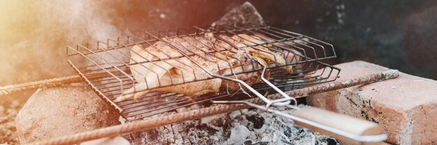 Foto hühnerfleisch wird im herbst auf einem lagerfeuer auf dem boden auf grillenden kohlen gebraten.