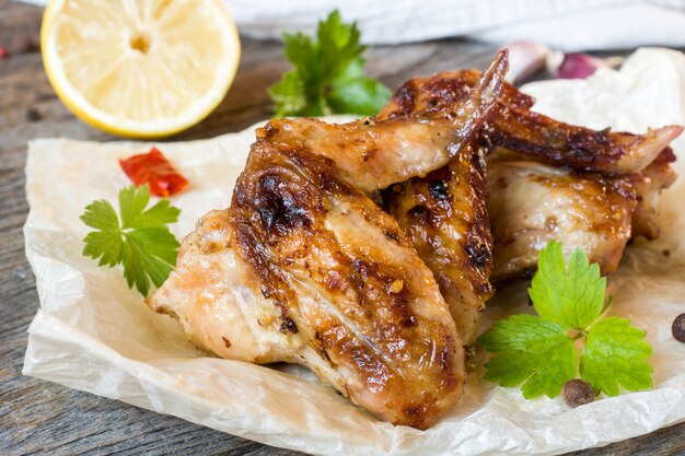 Hühnerflügel backten auf Grill mit frischen Kräutern, Zitrone auf Holztisch.