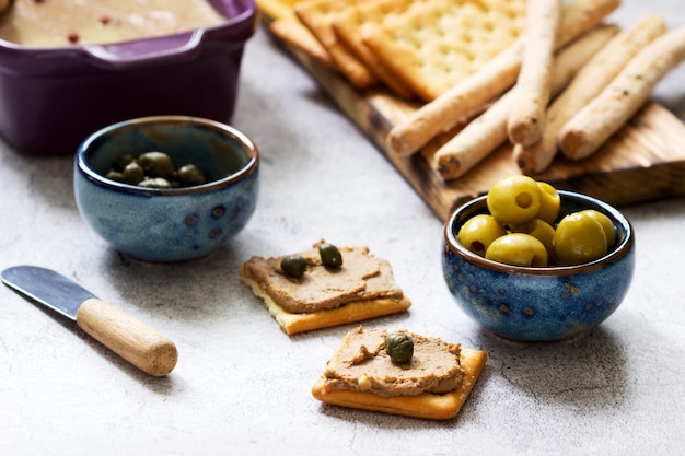 Hühnerleber, Zwiebel und Karottenpaste, serviert mit Crackern, Grissini, Oliven, Kapern und Champagner.