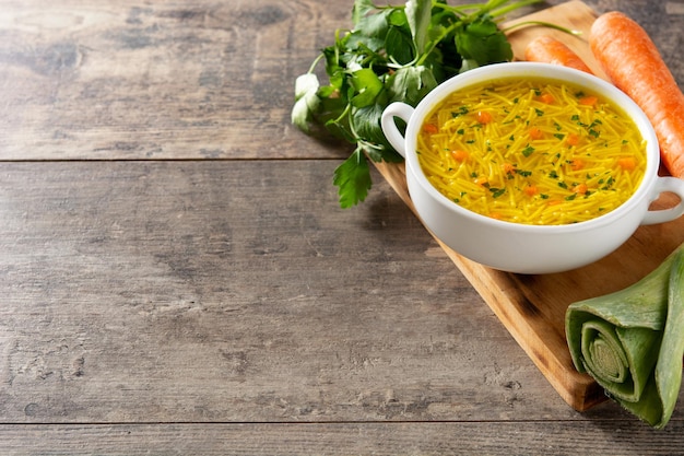 Hühnernudelsuppe in weißer Schüssel auf Holztisch