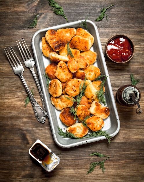 Hühnernuggets auf einem Stahltablett mit Sauce.