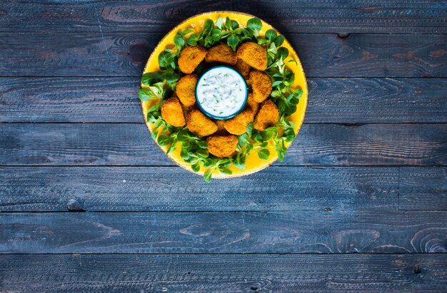 Foto hühnernuggets mit jogurtsoße auf einem hölzernen hintergrund