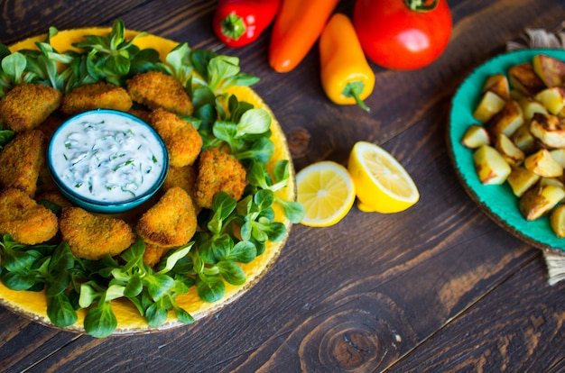 Hühnernuggets mit Jogurtsoße auf einem Holztisch