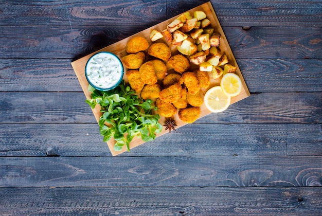 Hühnernuggets mit jogurtsoße auf einer holzoberfläche