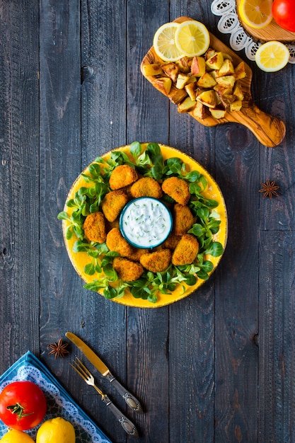 Hühnernuggets mit Jogurtsoße auf Holz