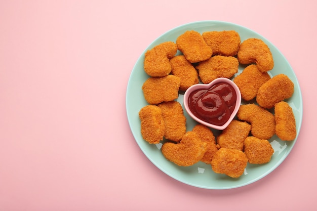 Hühnernuggets mit Ketchup auf einem Teller auf rosa Hintergrund
