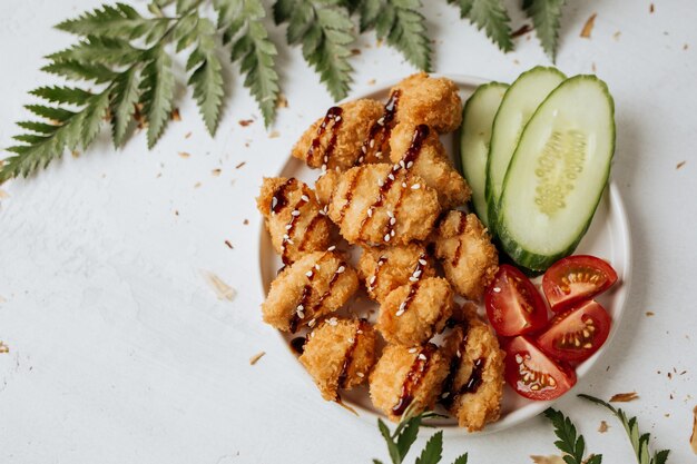 Hühnernuggets werden mit frischer Gurke und Tomaten serviert