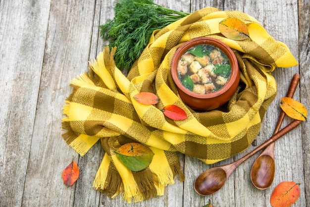 Hühnersuppe mit Croutons in einem Tontopf.