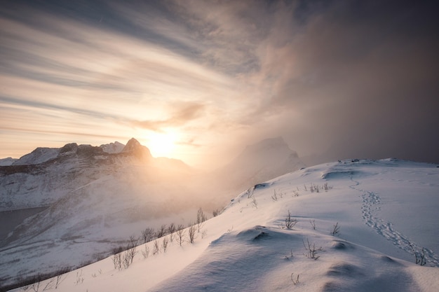 Huella en la colina de nieve con amanecer en la cordillera