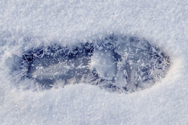 Una huella humana en la nieve y grandes copos de nieve.