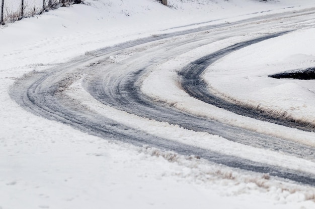 Huellas del coche en una carretera nevada en invierno