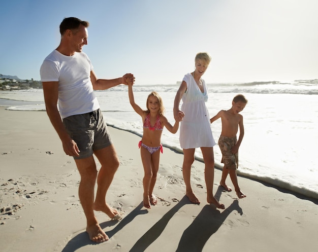 Huellas familiares en la arena Una joven familia feliz caminando juntos por la playa bajo el sol