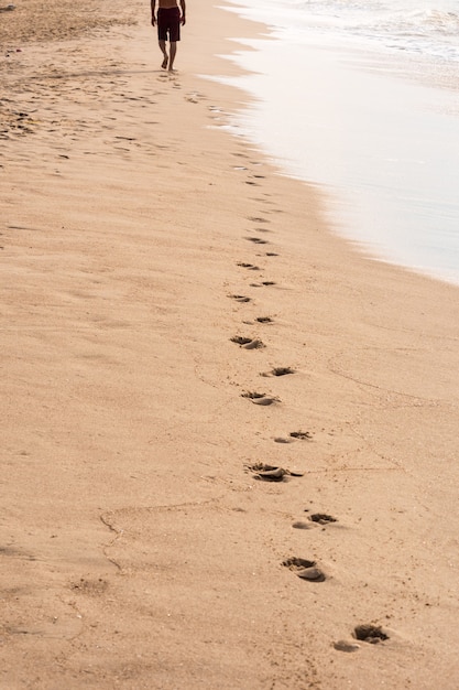 Huellas de un hombre caminando en la playa. Concepto de viaje