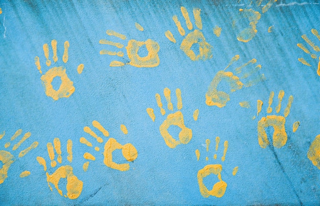 Foto huellas de manos en la pared huellas amarillas en una pared azul el fondo del concepto de amistad