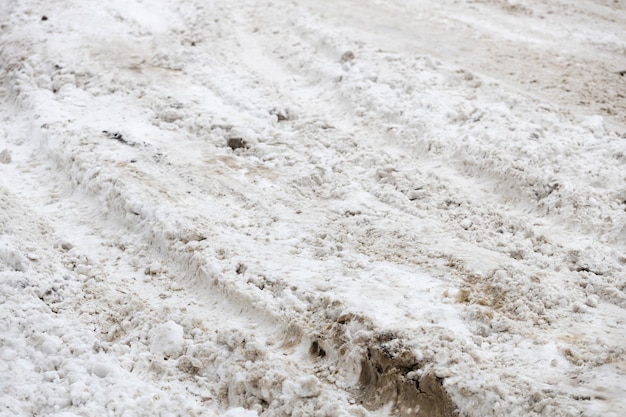 Huellas de neumáticos de coche en la nieve. caminos sucios de las calles de la ciudad en invierno