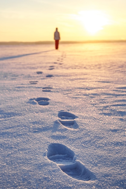 Huellas en la nieve. La niña se va hacia el atardecer.