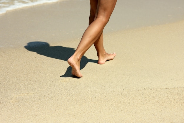 Huellas de pies femeninos en la arena de la playa en verano