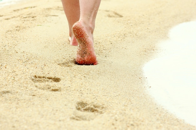 Huellas de pies femeninos en la arena de la playa