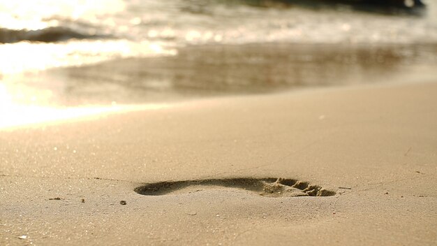 Foto huellas en la playa de arena y ola creciente