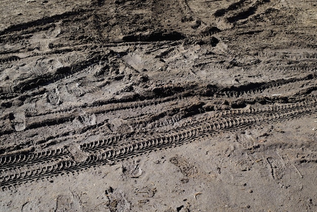 Huellas de tierra húmeda y marcas de neumáticos en el camino fangoso al aire libre Superficie de textura de la tierra del campo