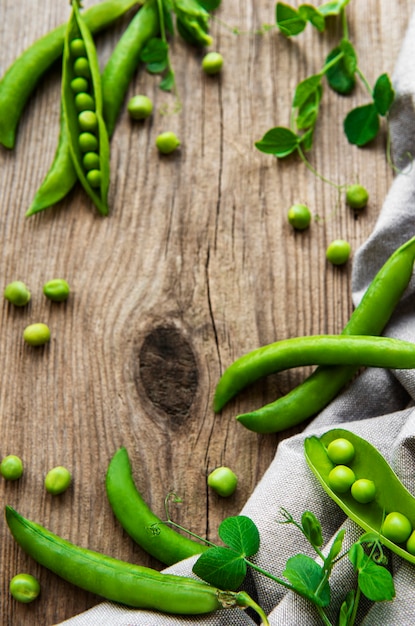 Foto hülsen von grünen erbsen mit erbsenblättern auf einer alten holzoberfläche