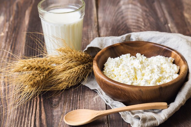 Hüttenkäse, Milch und Ähren auf rustikalem hölzernem Hintergrund. Milchprodukte für den jüdischen Urlaub Shavuot.