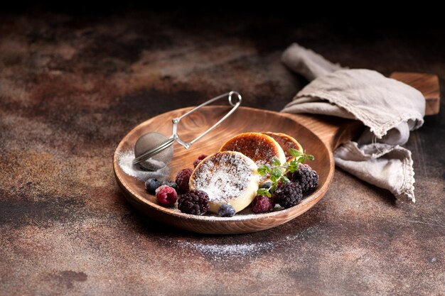 Hüttenkäse-Pfannkuchen Syrniki mit Puderzucker und Beeren