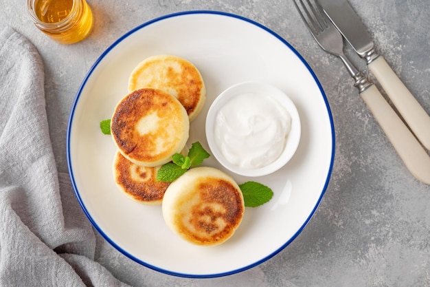 Hüttenkäse-Pfannkuchen Syrniki Ricotta Krapfen mit Honig und Sauerrahm Draufsicht Kopierraum