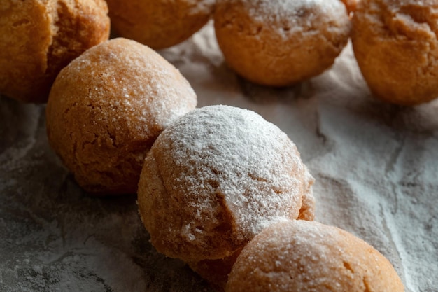 Hüttenkäsebällchen auf Holzspießen liegen auf Bastelpapier mit Puderzucker bestäubt