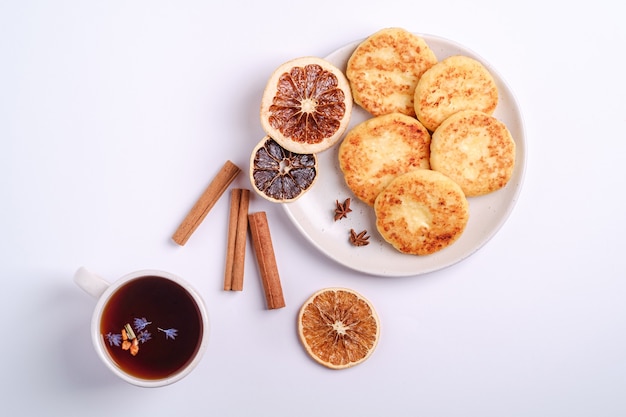 Hüttenkäsekrapfen mit heißem schwarzem aromatischem Tee, Weihnachtsfrühstücksstimmung mit Anis und Zimt auf weißem Hintergrund, Draufsicht