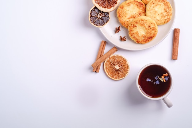 Hüttenkäsekrapfen mit heißem schwarzem aromatischem Tee, Weihnachtsfrühstücksstimmung mit Anis und Zimt auf weißem Hintergrund, Draufsichtkopierraum