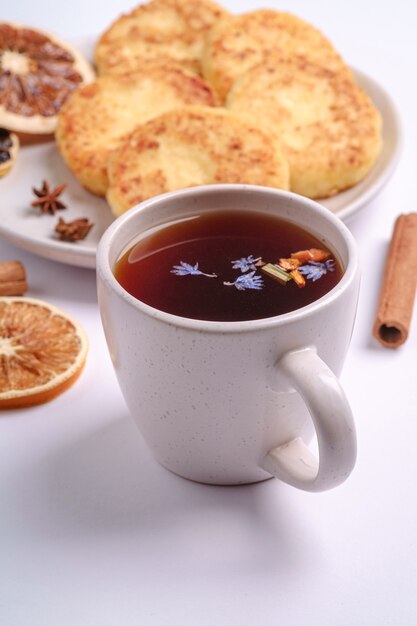 Hüttenkäsekrapfen mit heißem schwarzen aromatischen Tee, Weihnachtsfrühstücksstimmung mit Anis und Zimt auf weißem Hintergrund, Winkelansicht